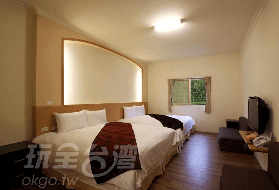 【瑞里民宿】詹德仁茶園民宿的三人房空間，配置兩張雙人床與一張單人床，牆面拱形燈槽設計為房間增添柔和氛圍，窗外可見綠意景色。