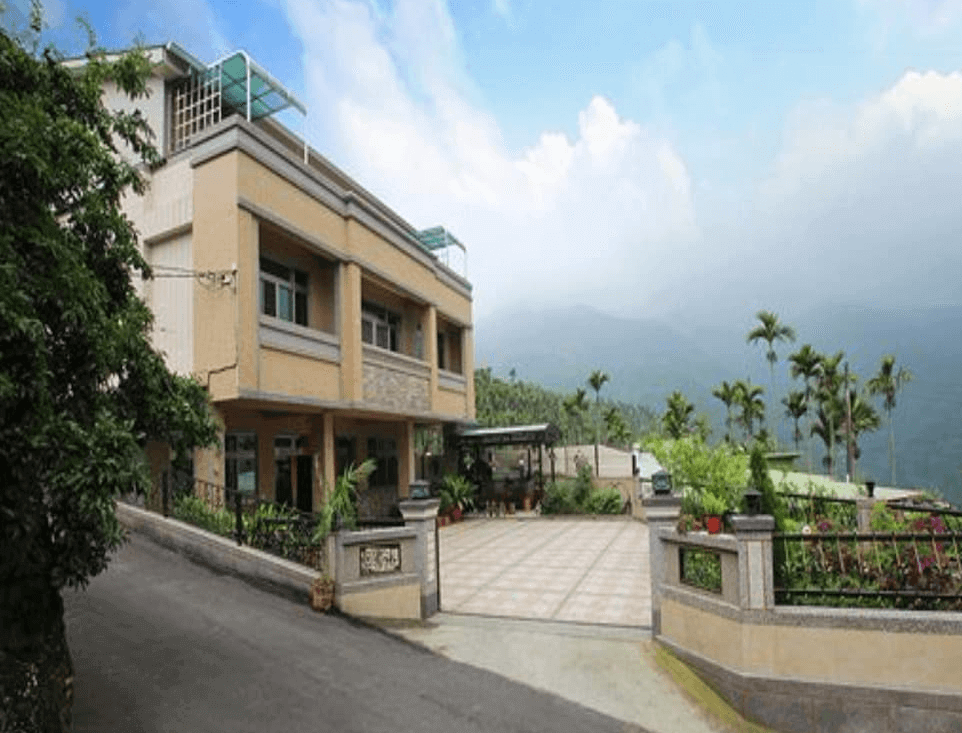 【瑞里民宿】詹德仁茶園民宿，兩層樓民宿建築，外觀為米黃色系，設有庭院與停車空間，四周環繞山景與茶園，自然景觀宜人。