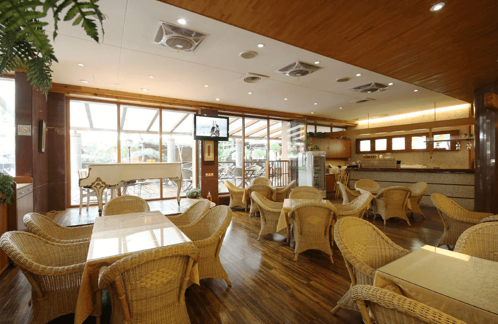 【谷關住宿】谷關 溫泉飯店的餐廳空間明亮寬敞，設有大量藤編座椅與玻璃桌面，裝潢以木質與大地色系為主。玻璃門外連接露台與鋼琴區，整體氛圍溫暖悠閒，是用餐與下午茶的理想場域。
