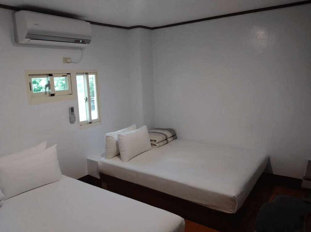 【蘇澳住宿】金華冷泉溫泉旅館的雙人房，設有兩張單人床，白色牆面搭配木質地板，房內備有分離式冷氣與窗戶，空間整潔明亮，適合小家庭或好友入住。