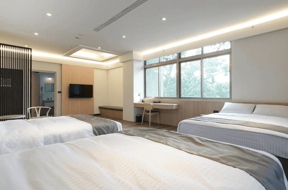 【關子嶺溫泉】“白河住宿”關子嶺富野溫泉會館的簡約風格三床家庭房，設有大片窗戶與自然採光，室內配有書桌、電視與舒適座椅，整體空間寬敞明亮。