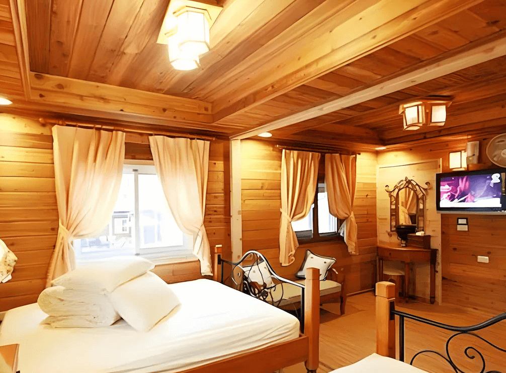 【瑞里民宿】阿漢的家民宿以溫暖原木打造的鄉村風雙人房，房內配有典雅的鐵藝床架、梳妝台、電視與柔和的燈光，窗簾與木牆呼應出自然溫馨氛圍。