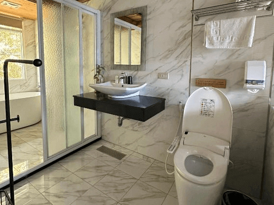 【瑞里民宿】阿漢的家民宿的浴室，牆面與地板為大理石紋磚，設有免治馬桶、懸空洗手台與乾濕分離淋浴空間，整體明亮整潔。