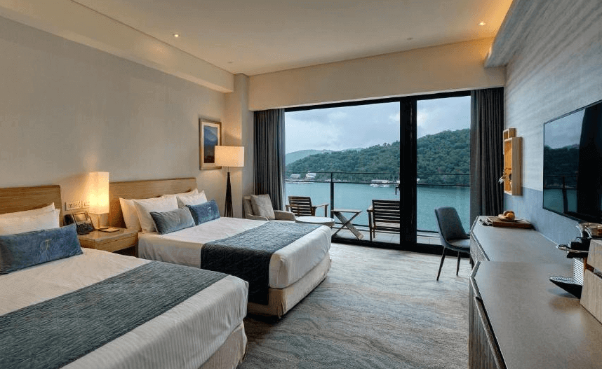 【台灣最貴飯店】雲品溫泉酒店擁有日月潭湖景的雙床客房，大片落地窗與陽台可欣賞寧靜湖面與山巒環繞，房間裝潢簡約雅緻，配有舒適座椅與多功能書桌。