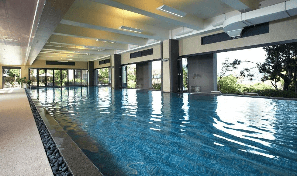 【台灣最貴飯店】雲品溫泉酒店設有寬敞明亮的室內溫水游泳池，採用大片玻璃窗引入自然光與綠意景觀，適合全年齡層旅客休閒運動與放鬆身心。