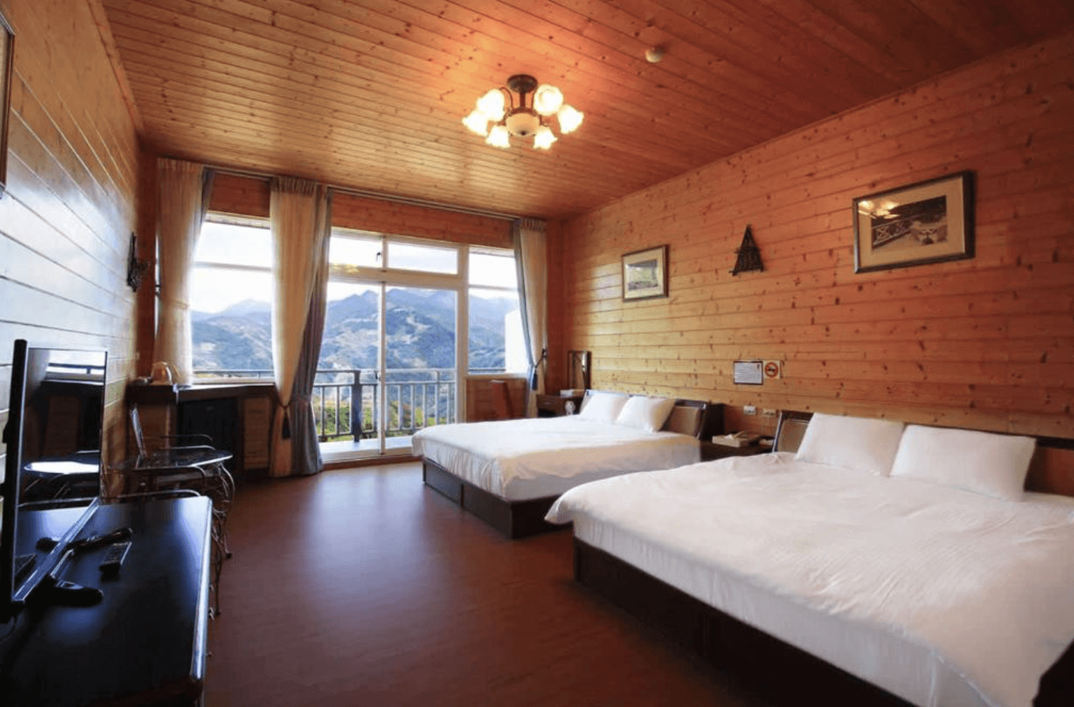 【清境農場住宿】雲濛仙境民宿以全木質裝潢打造的溫馨四人房，牆面與天花板皆採原木設計，配有兩張雙人床與基本家具，房內空間寬敞，落地窗外即是絕美山景，營造出溫暖放鬆的渡假氛圍。