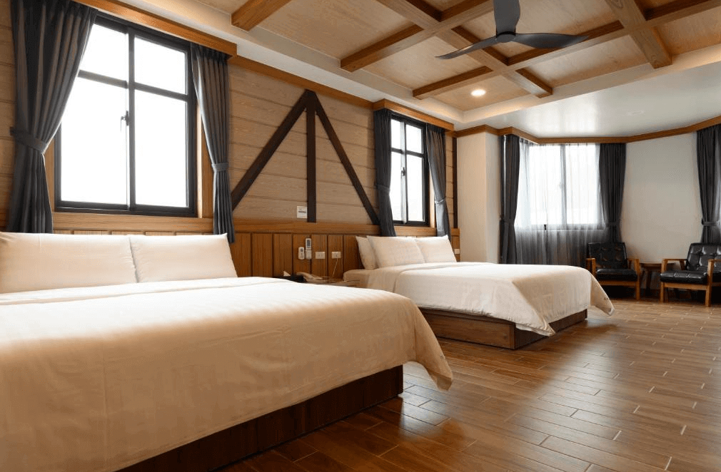 【瑞里民宿】高帝園茶業民宿的四人房，兩張雙人床旁設有大面窗戶與沙發座位區，整體裝潢採用木質與簡約設計，營造出舒適溫馨的居住氛圍。