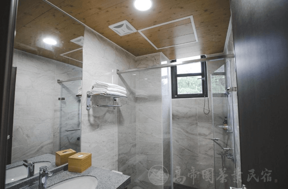 【瑞里民宿】高帝園茶業民宿的浴室，設有乾濕分離的淋浴空間、大理石牆面與洗手台上方的大鏡子，整體乾淨明亮並附有毛巾與備品。