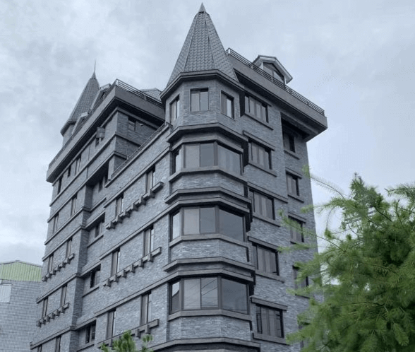 【瑞里民宿】高帝園茶業民宿的歐式城堡風格的灰磚建築，屋頂尖塔造型獨特，窗戶設計整齊有致，整體建築充滿特色與氣勢。