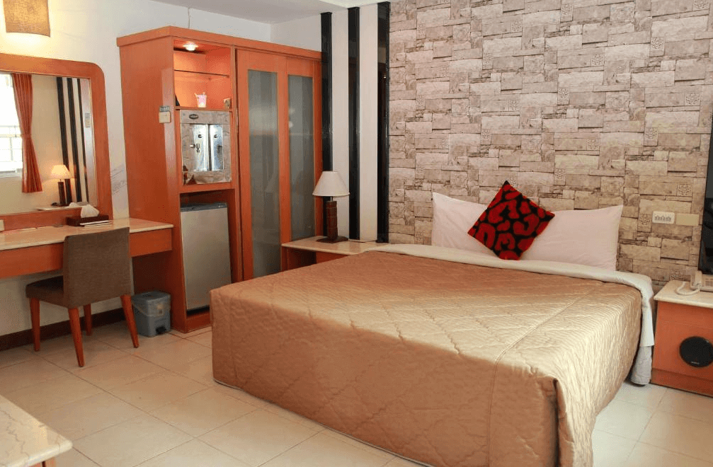 【關子嶺溫泉】“白河住宿”麗湯溫泉渡假山莊的典雅雙人房設有一張大床，牆面為仿石材紋理裝飾，附有木質衣櫃、梳妝台與冰箱，空間簡潔實用。