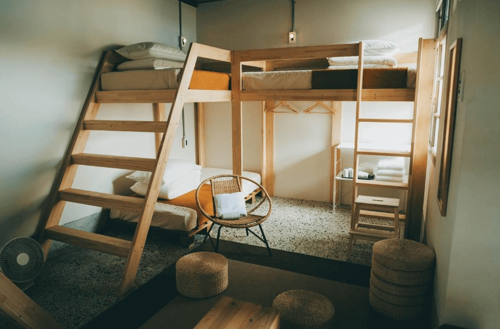 【左營住宿】Goonnight Hostel 軍旅舍溫馨多人上下舖房型，木質上下舖搭配藤編坐墊與休閒椅，空間寬敞溫馨，適合朋友或家庭共享，地板為磨石子地面，營造復古氛圍。