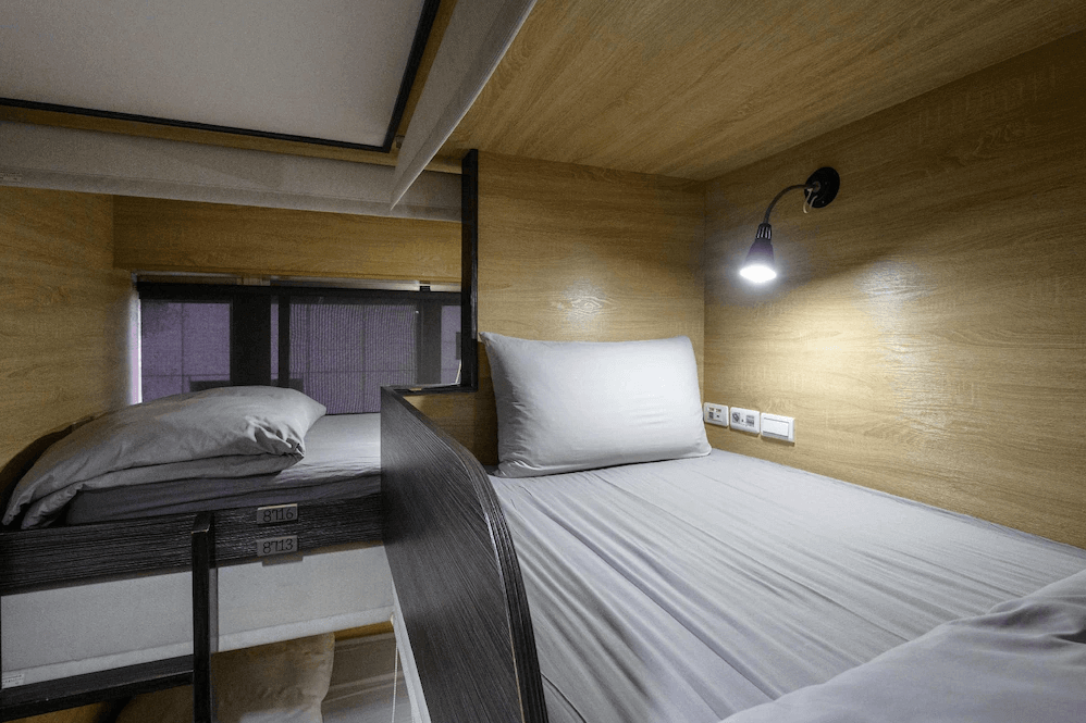 【台北車站青年旅館】WORK INN 北車館的單人膠囊床位，設有閱讀燈、插座與隔板，空間溫馨舒適，床鋪整潔，提供獨立且安靜的休憩環境。