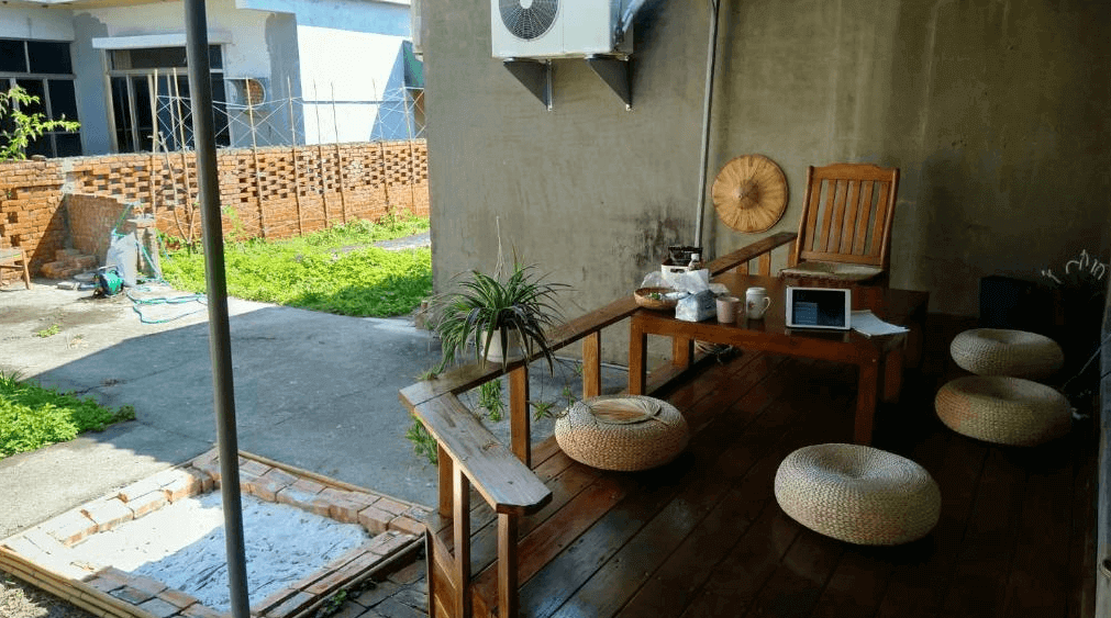 【左營住宿】丈引小院庭院與露台茶席區，民宿庭院旁設有木質露台，配置藤編坐墊與木桌，適合戶外品茶放鬆，環境寧靜並保留老宅元素。