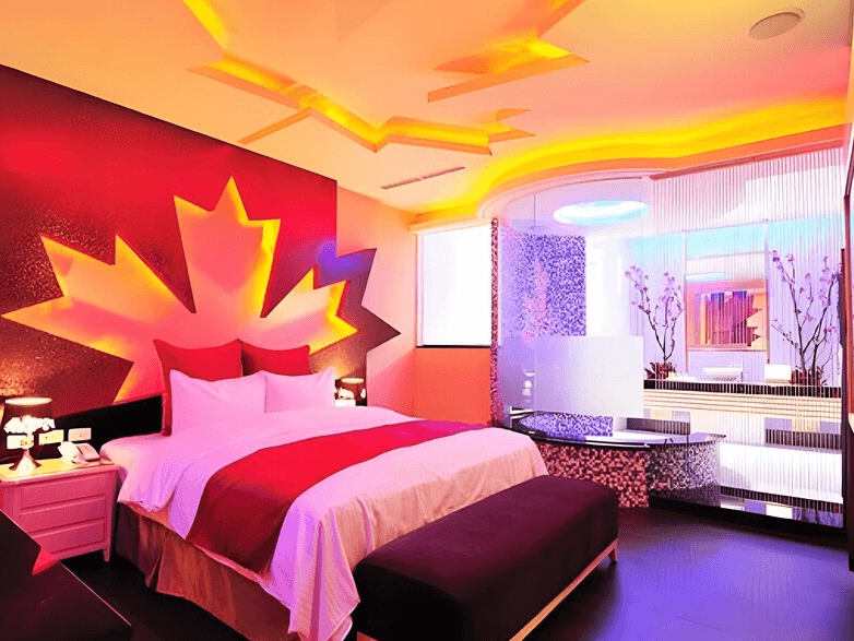 【龍潭住宿】伊加伊時尚汽車旅館，充滿視覺張力的情境主題房，以鮮紅與金黃漸層設計的大型楓葉圖案作為牆面主軸，天花板搭配多層次燈光線條，打造出濃烈現代感與浪漫氛圍。床旁設有玻璃隔間與摩登梳妝空間，整體色調大膽華麗，極具特色。