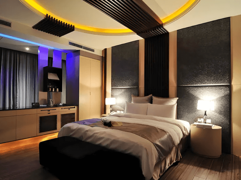 【龍潭住宿】伊加伊時尚汽車旅館的套房，以深灰與木質元素融合設計，搭配圓形天花燈光與黑色線條裝飾，呈現出時尚低調的氛圍。房內備有咖啡機、辦公桌與充足收納空間，適合商務旅客入住。