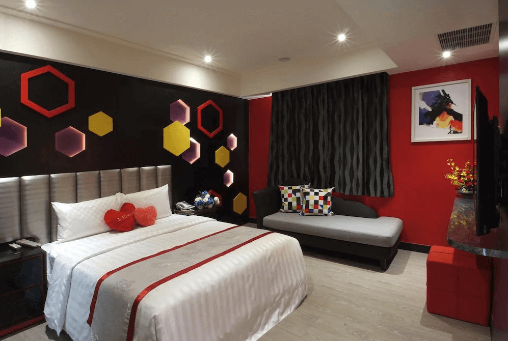【楊梅住宿】凱萊汽車旅館的主題雙人房，以黑紅配色為主，牆面裝飾立體幾何燈飾與撞色靠枕，床上擺有愛心抱枕與毛巾，是情侶入住的理想選擇。