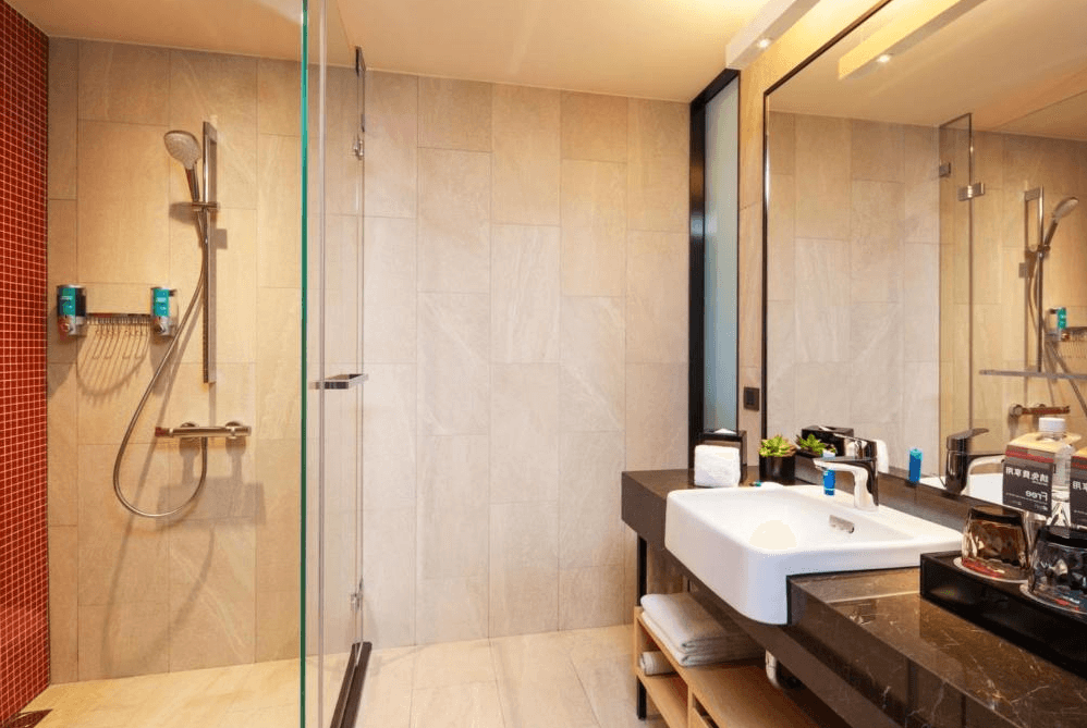 【台北寵物友善住宿】台北北投雅樂軒酒店的現代浴室，設有獨立淋浴間與玻璃隔間，牆面部分採用紅磚馬賽克設計，搭配大面鏡與白色洗手台，備品整齊齊全。