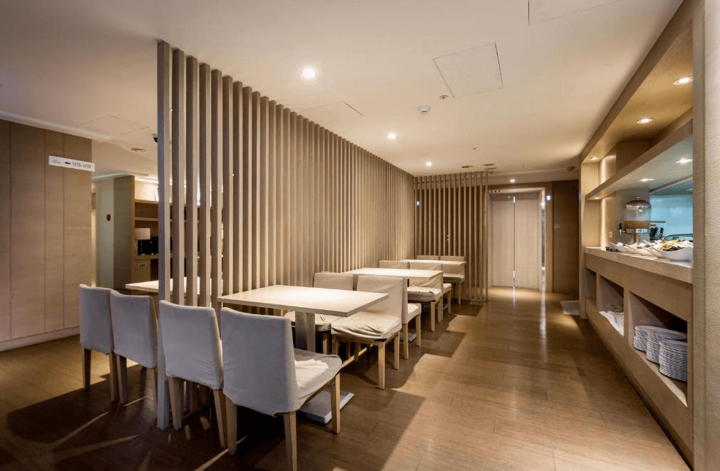 【三重住宿】台北薇米商旅的餐廳空間，座位區以柔和燈光與木質隔板營造溫馨氛圍。餐檯旁設有自助取餐區，提供簡易早餐，整體空間安靜舒適，適合悠閒用餐。