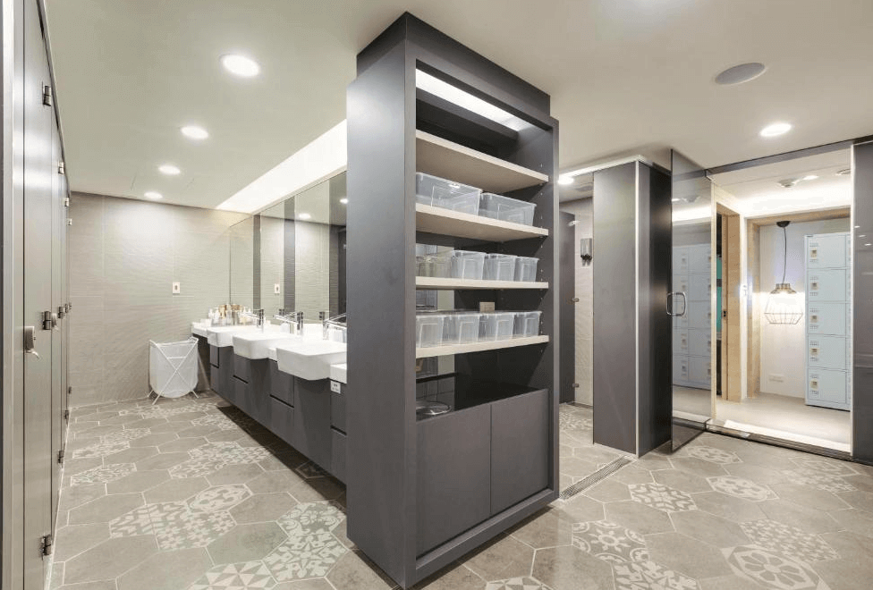 【台北車站青年旅館】台灣青旅膠囊旅店的共用衛浴空間，設有多個洗手台與大型鏡面，並提供透明置物箱與置衣籃，地面採用花紋拼貼磁磚，整潔有序、機能齊全。