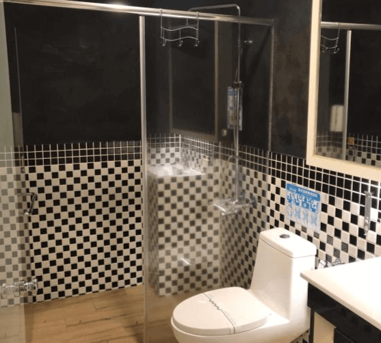 【楊梅住宿】君洋城堡的衛浴空間，設有黑白棋盤格磁磚牆面，乾濕分離淋浴間與透明玻璃門，搭配簡潔白色馬桶與洗手台，整體乾淨明亮。