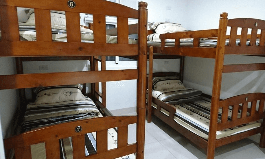 【左營住宿】國泰旅社上下舖背包客房型，房內擺設兩組實木上下舖床位，共可容納四人，床鋪整齊並配有條紋床單，空間簡潔實用，適合團體入住。
