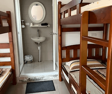 【左營住宿】國泰旅社背包客房內衛浴設施，上下舖床位旁設有獨立衛浴空間，內有洗手台與圓形鏡面，衛浴設施簡約齊全，提供基本便利。