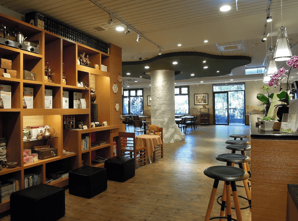 【杉林溪住宿】孟宗山莊大飯店的內部公共空間，結合書牆、木質地板與吧檯設計，陳列各式文創商品與擺飾，營造溫暖舒適的閱讀與用餐環境。