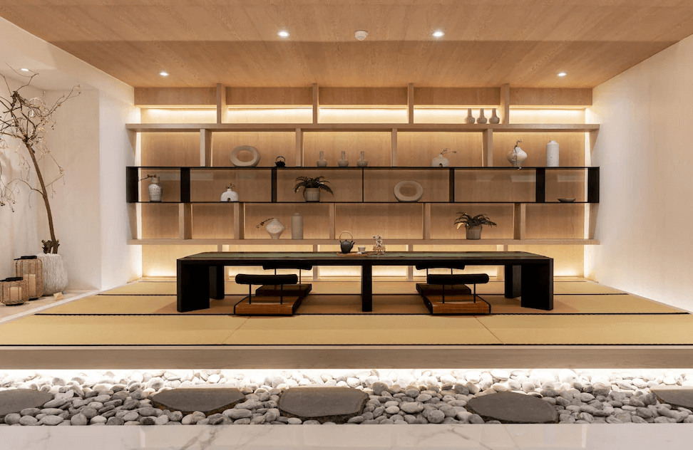 【一中街住宿】宿野行旅的日式風格公共交誼空間，鋪設榻榻米地板，中央設有矮桌與坐墊，背牆展示精緻陶器與盆栽，並以間接照明營造靜謐禪意氛圍。