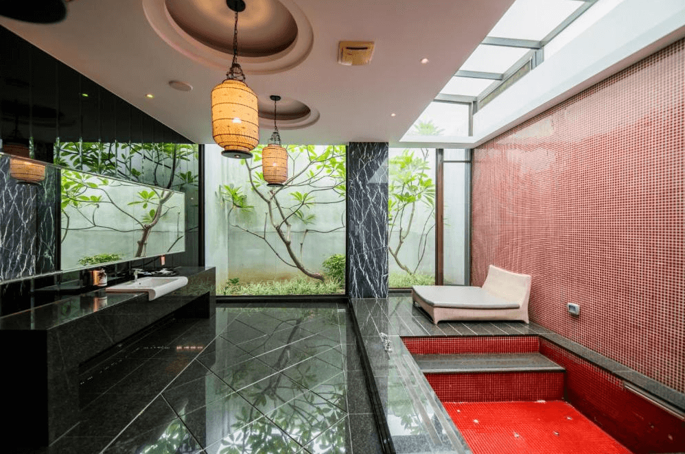 【草屯住宿】山月景緻旅館的私人湯屋空間，配有紅色馬賽克磚浴池、黑色大理石地板與洗手台，大片落地窗外可見綠意庭園，並設有一張躺椅休憩，整體空間兼具自然與設計美感。