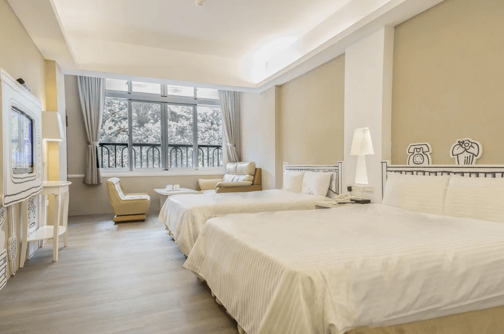 【杉林溪住宿】明山森林會舘的雙床客房，牆面裝飾卡通插圖與立體造型床頭板，設有沙發椅與大片窗戶，營造輕鬆愉悅的親子氛圍。