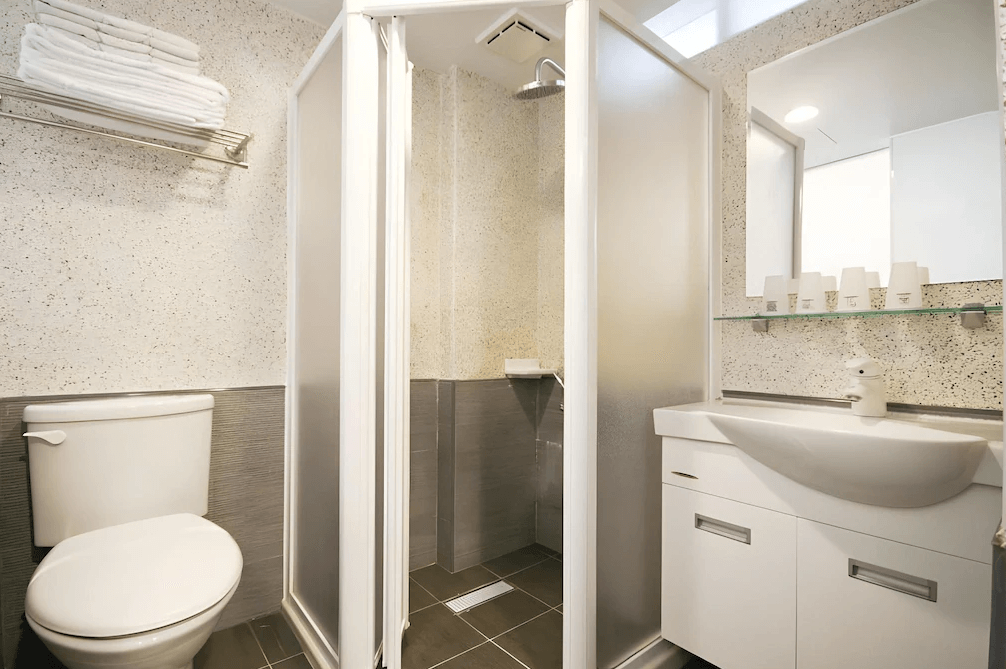 【杉林溪住宿】明山森林會舘的衛浴空間，配置乾濕分離淋浴間、洗手台與馬桶，整體潔淨明亮，具備基本備品與毛巾架。