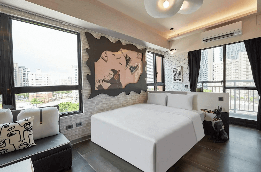 【左營住宿】星澄風旅藝術風格雙人房，房內以街頭藝術風格打造，搭配特色塗鴉牆與大型床鋪，三面採光設計讓空間明亮通透，並配有沙發與可愛狗型裝飾擺設。