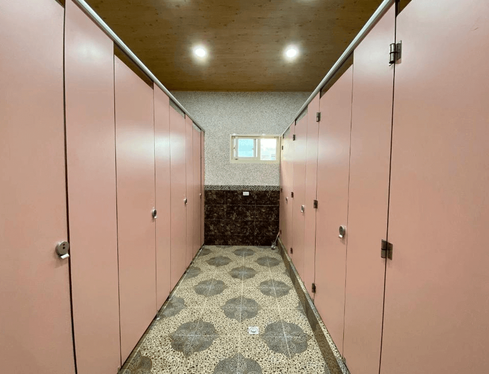 【龍潭住宿】晃晃印地安帳篷營區內設有整潔明亮的公共廁所，粉紅色門板與花磚地面設計清新可愛。空間分隔清楚、維持良好清潔度，提供露營住客方便又舒適的如廁環境。