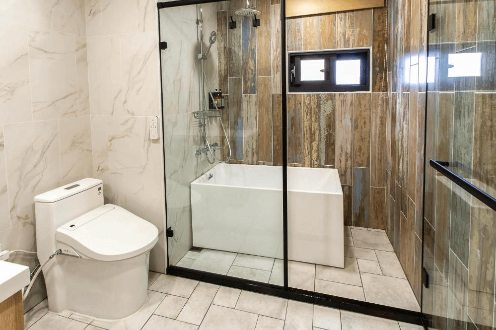 【杉林溪住宿】晨煦行旅的衛浴空間，設有免治馬桶、獨立淋浴間與浴缸，牆面採用仿大理石與木紋磁磚設計。