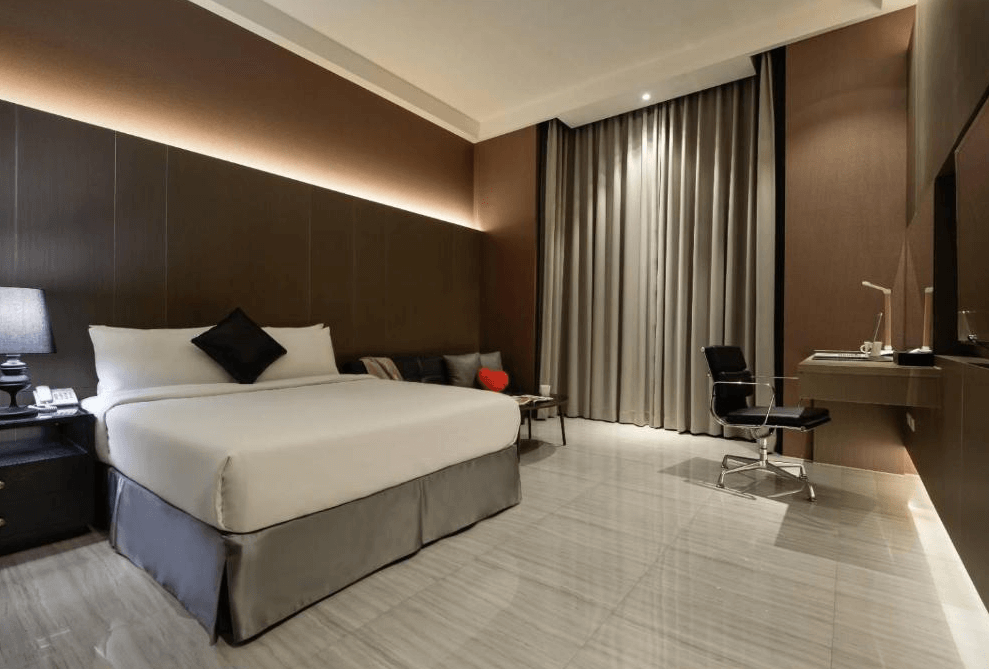 【草屯住宿】沐悅時尚精品旅館的雙人房，房內設有一張大床，搭配灰黑色調的牆面與窗簾，右側為辦公書桌與人體工學椅，整體空間乾淨俐落，營造靜謐舒適的休憩氛圍。