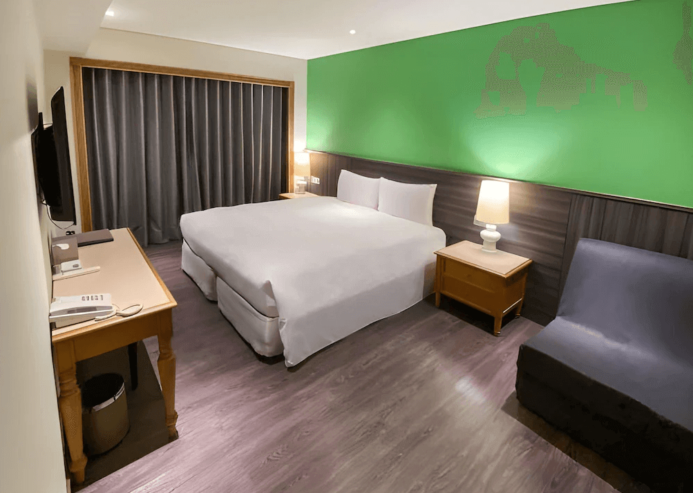 【台北小巨蛋住宿】洛碁大飯店三貝茲的雙人房設計，搭配綠色主題牆面與木質傢俱，空間寬敞舒適，適合休閒或商務旅客入住。