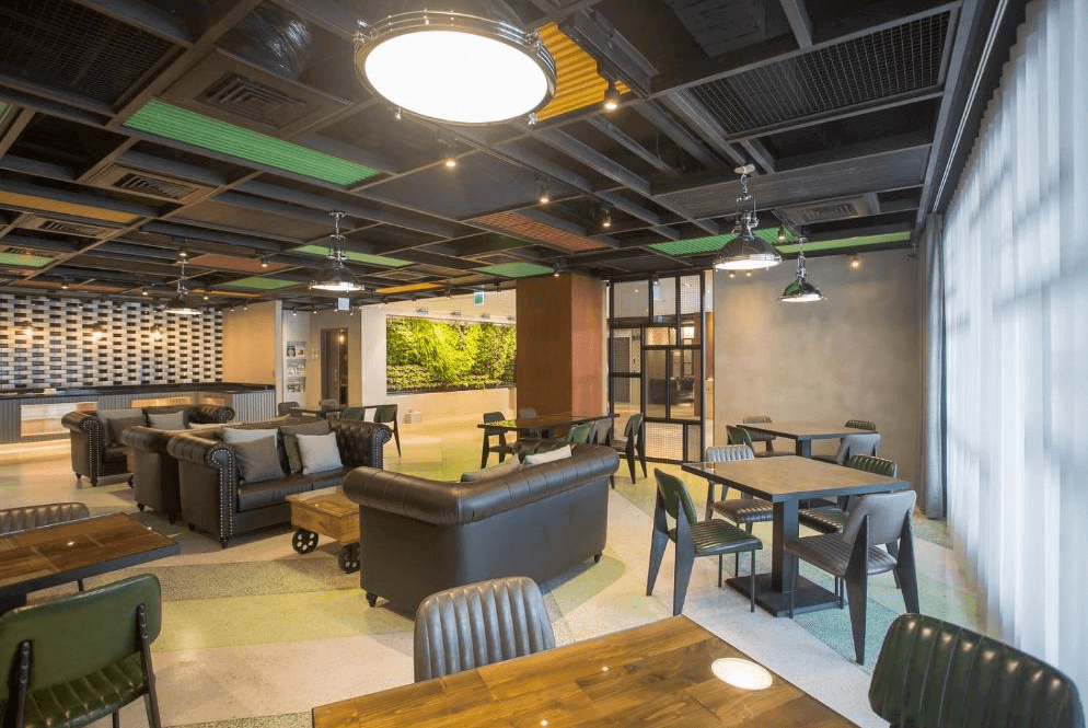 【台北小巨蛋住宿】洛碁大飯店三貝茲的大廳空間，配有多組沙發與木質桌椅，適合旅客放鬆聊天或休憩，氛圍活潑且具設計感。