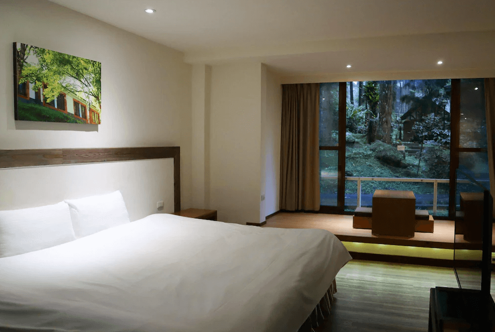 【杉林溪住宿】溪頭福華渡假飯店的雙人房，房內設有大片落地窗與和式座位區，可眺望窗外翠綠森林景致，營造靜謐氛圍。