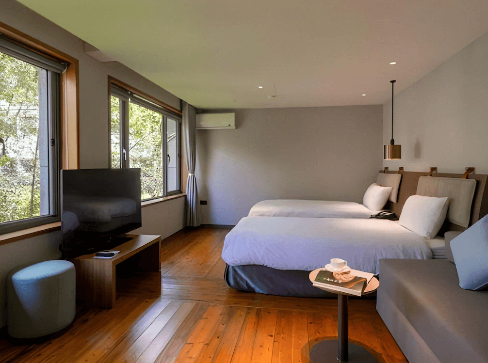 【杉林溪住宿】溪頭福華渡假飯店的雙床客房，搭配原木地板與自然色調裝潢，配有沙發座椅與大面窗景，展現自然舒適風格。