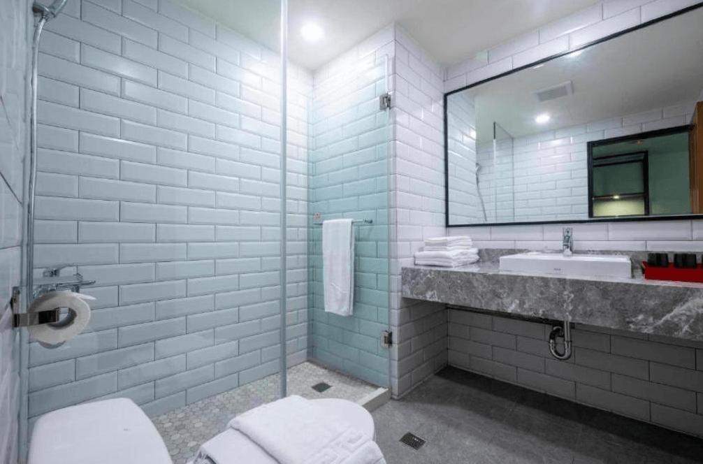 【杉林溪住宿】溪頭福華渡假飯店的衛浴，淺藍白磁磚設計，設有乾濕分離淋浴間與大面鏡洗手台，整體風格清新潔淨。