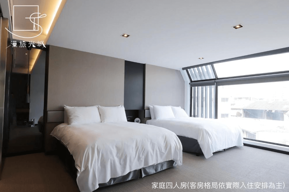 【一中街住宿】漫旅光城的家庭四人房，配有兩張雙人床，大片斜面落地窗引入充足自然光，視野開闊、空間寬敞明亮，適合親子或好友同行入住。