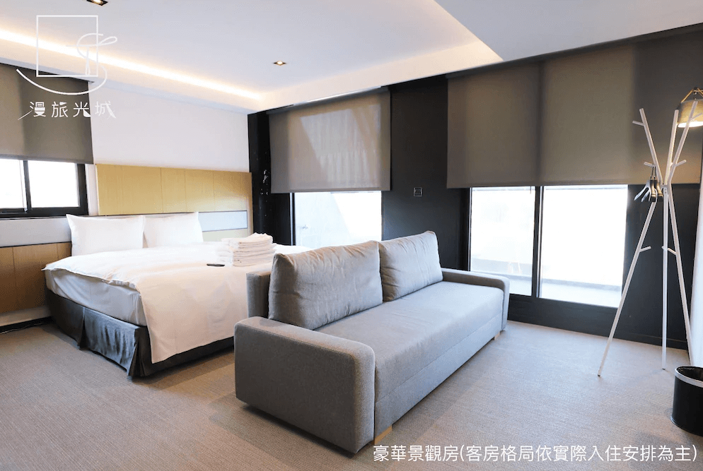 【一中街住宿】漫旅光城的豪華景觀房，配有一張雙人床與現代風格沙發，大片窗景與柔和燈光營造舒適氛圍，空間感十足且注重隱私與採光。