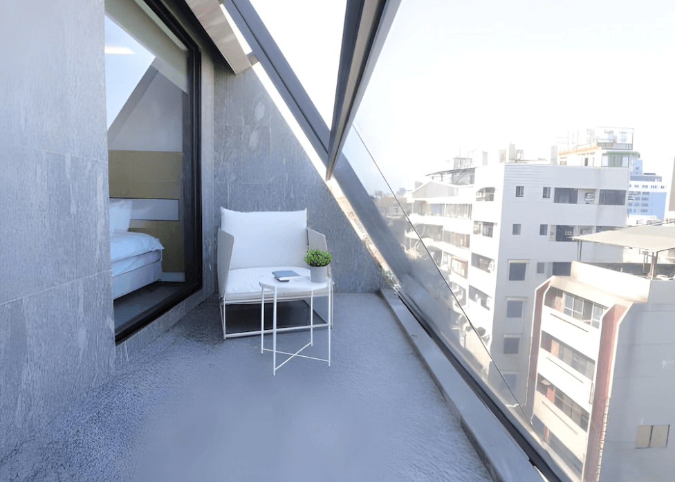 【一中街住宿】漫旅光城，獨特斜面玻璃景觀陽台，擺放簡約風格座椅與小茶几，可眺望城市風景，享受陽光與靜謐片刻，與室內空間巧妙連通。