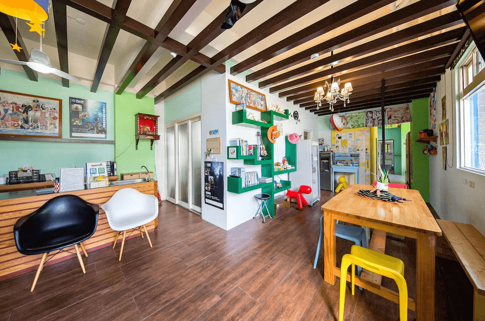 【綠島住宿】火燒島潛水度假中心的接待大廳與交誼廳，設有原木餐桌、閱讀區與彩色座椅，牆面裝飾潛水相關海報與玩具，氛圍溫馨且充滿童趣。