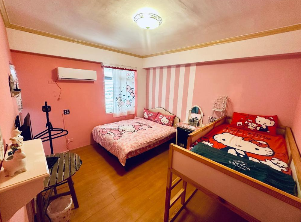 【綠島寵物友善住宿】燈光夏的親子房型，一大床搭配一張兒童床，床組皆為Hello Kitty主題設計，房內設有梳妝台、電視與冷氣，營造出活潑又溫暖的親子氛圍。