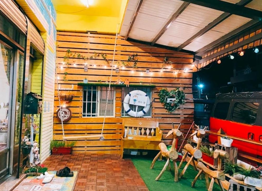 【綠島寵物友善住宿】燈光夏木質牆面與地板構成的戶外休憩區，佈置有吊椅、鞦韆與手工木馬裝飾，小燈串點綴營造出溫馨夜晚氛圍，是拍照與放鬆的好去處。