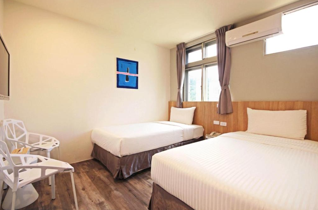 【綠島寵物友善住宿】綠島 統祥大飯店的兩張單人床設置於乾淨明亮的客房中，房內採用木質裝潢與大面窗戶，自然光充足，牆上掛有簡約藝術畫作，提供溫馨住宿體驗。