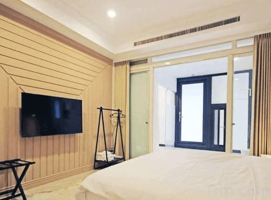 【綠島住宿】綠島House16的雙人房，設有壁掛電視與開放式衣架，落地玻璃門通往陽台空間，整體色調溫暖柔和，充滿舒適感。