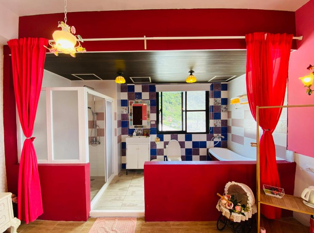 【綠島寵物友善住宿】綠島寧靜海潛水-城堡館的開放式衛浴空間，設有淋浴間、馬桶與浴缸，牆面以紅藍拼接磁磚妝點，並以紅色布簾區隔空間，裝飾品與燈飾提升整體浪漫感受。