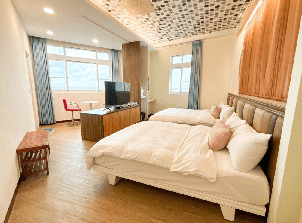 【綠島住宿】綠島海灣會館的四人房空間，配有兩張雙人床、電視櫃與獨立座位區，天花板以圓點造型裝飾，整體風格溫馨典雅，適合家庭入住。